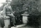 Tandläkare Gunnar Högberg sittande på en mur bredvid en klassisk urna i Båstad, Skåne 1922.