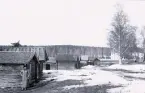 Bild av timmerbyggnader till vänster i bild samt en större byggnad bakom träden i Rättvik, Dalarna 1926.