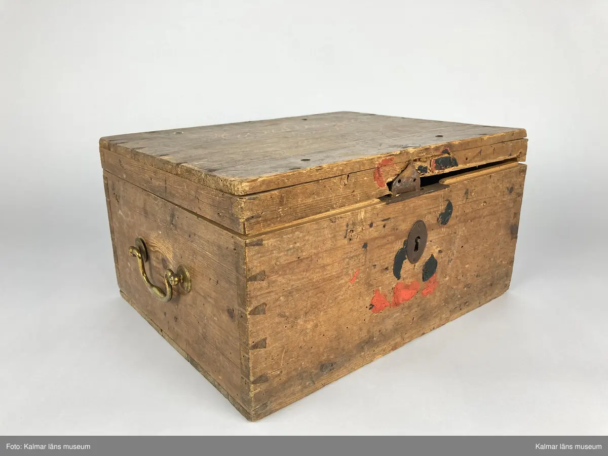 KLM 46971:1. Kista. Av trä med lås och beslag av järn samt på kortsidorna handtag av mässing varav det ena saknas. Kistan har rektangulär form och lock. Skriven text i rött på locket: Handlingar rörande läroverket. Ovanför text i svart: F W ... På undersidan av kistan målade siffror i svart. På fronten runt låset diverse lacksigill i svart och rött. Kistan har innehållit diverse handlingar rörande Kalmar högre allmänna läroverk. Väl använd.