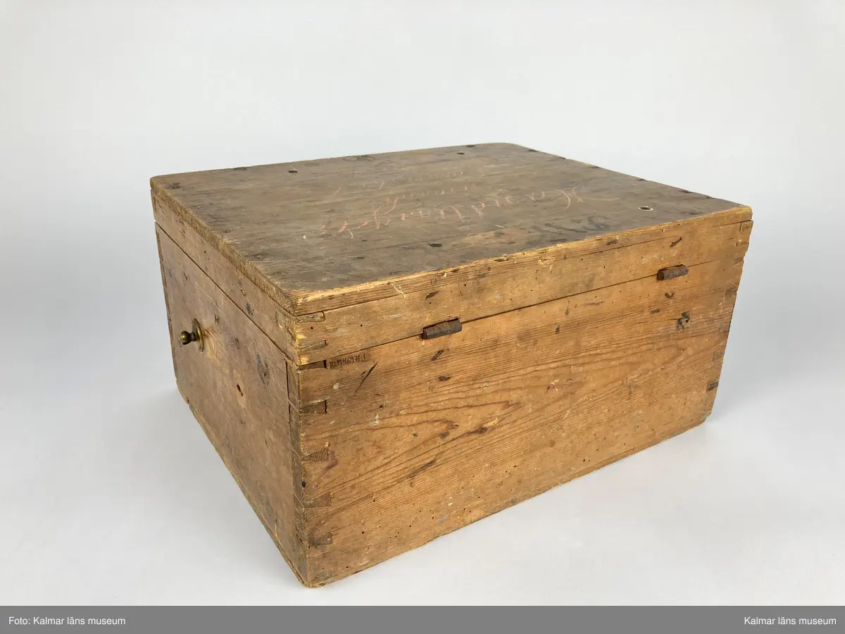 KLM 46971:1. Kista. Av trä med lås och beslag av järn samt på kortsidorna handtag av mässing varav det ena saknas. Kistan har rektangulär form och lock. Skriven text i rött på locket: Handlingar rörande läroverket. Ovanför text i svart: F W ... På undersidan av kistan målade siffror i svart. På fronten runt låset diverse lacksigill i svart och rött. Kistan har innehållit diverse handlingar rörande Kalmar högre allmänna läroverk. Väl använd.