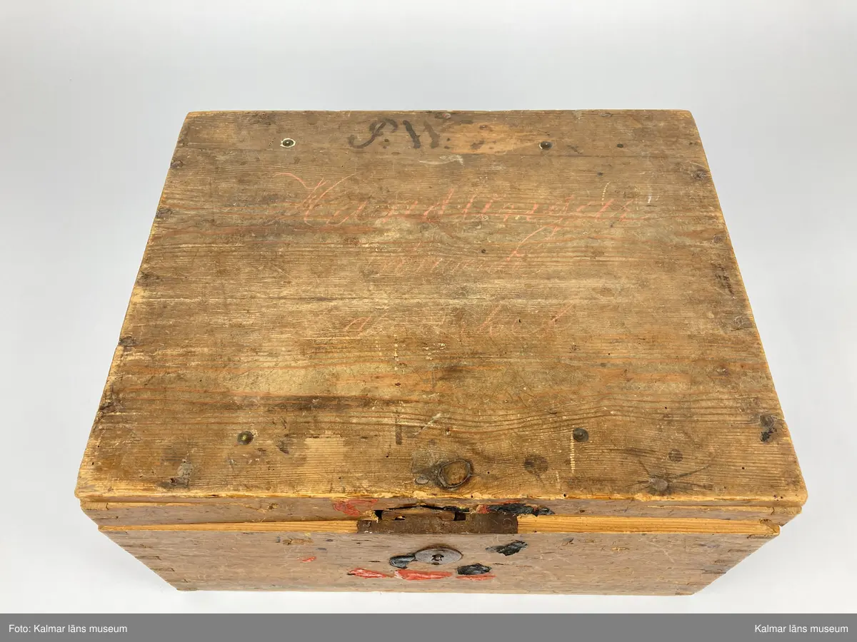 KLM 46971:1. Kista. Av trä med lås och beslag av järn samt på kortsidorna handtag av mässing varav det ena saknas. Kistan har rektangulär form och lock. Skriven text i rött på locket: Handlingar rörande läroverket. Ovanför text i svart: F W ... På undersidan av kistan målade siffror i svart. På fronten runt låset diverse lacksigill i svart och rött. Kistan har innehållit diverse handlingar rörande Kalmar högre allmänna läroverk. Väl använd.