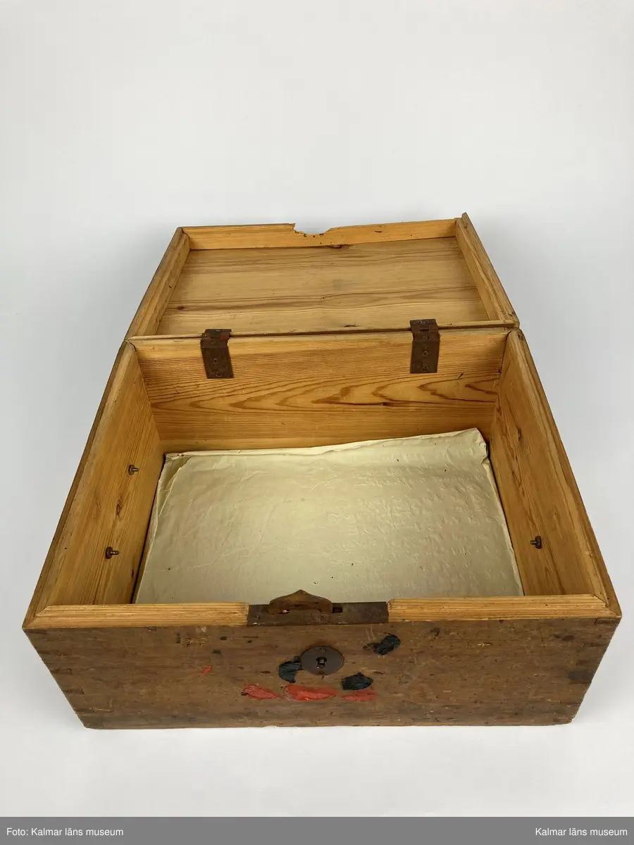 KLM 46971:1. Kista. Av trä med lås och beslag av järn samt på kortsidorna handtag av mässing varav det ena saknas. Kistan har rektangulär form och lock. Skriven text i rött på locket: Handlingar rörande läroverket. Ovanför text i svart: F W ... På undersidan av kistan målade siffror i svart. På fronten runt låset diverse lacksigill i svart och rött. Kistan har innehållit diverse handlingar rörande Kalmar högre allmänna läroverk. Väl använd.