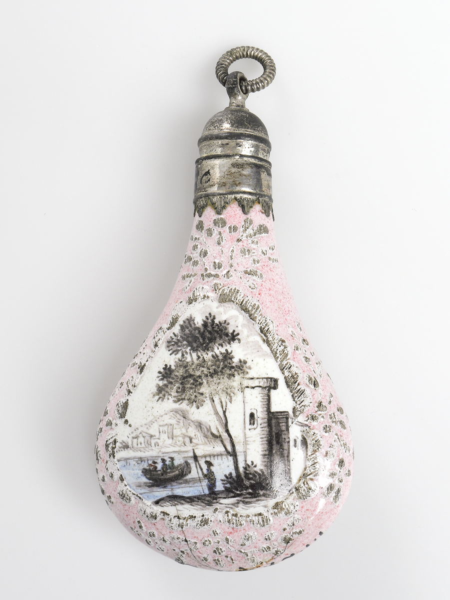 Luktflaska av rosafärgat porslin. Bild av träd och byggnad vid vatten med personer i båt, snarlika motiv på båda sidor. Droppformig med skruvkork av vit metall. För förvaring av luktsalt. 

Inskrivet i huvudbok år 1969.
