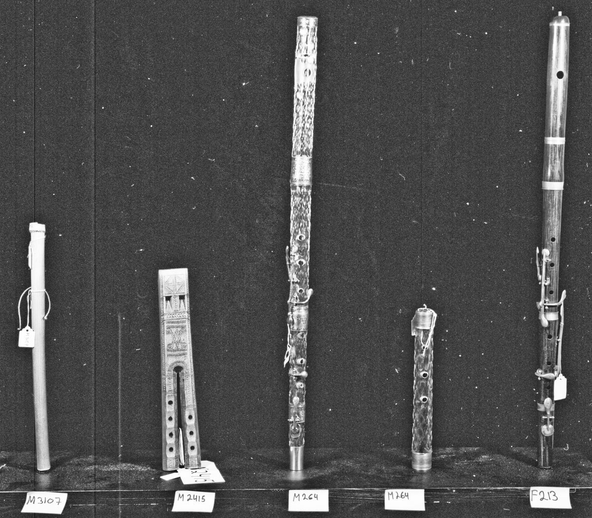 Tvärflöjt i mörkbrunt trä med ringar av silver. 5 delar. Konisk form. Spricka i päronet. En bit av ändlocket saknas. Nedersta ringen saknas. 6 klaffar av silver med kullagring och runda plattor. Tydliga spår av användning vid anblåsningshålet.