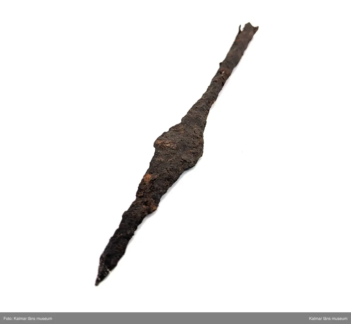 KLM 2498. Spjutspets. Lång med rombiskt blad. Holken är rund ner mot bladet men mer fyrkantig längre bak, där ett stycke trä sitter kvar.  Mått: längd 37 cm, därav holk 20 cm, bladets bredd 3,2 cm.