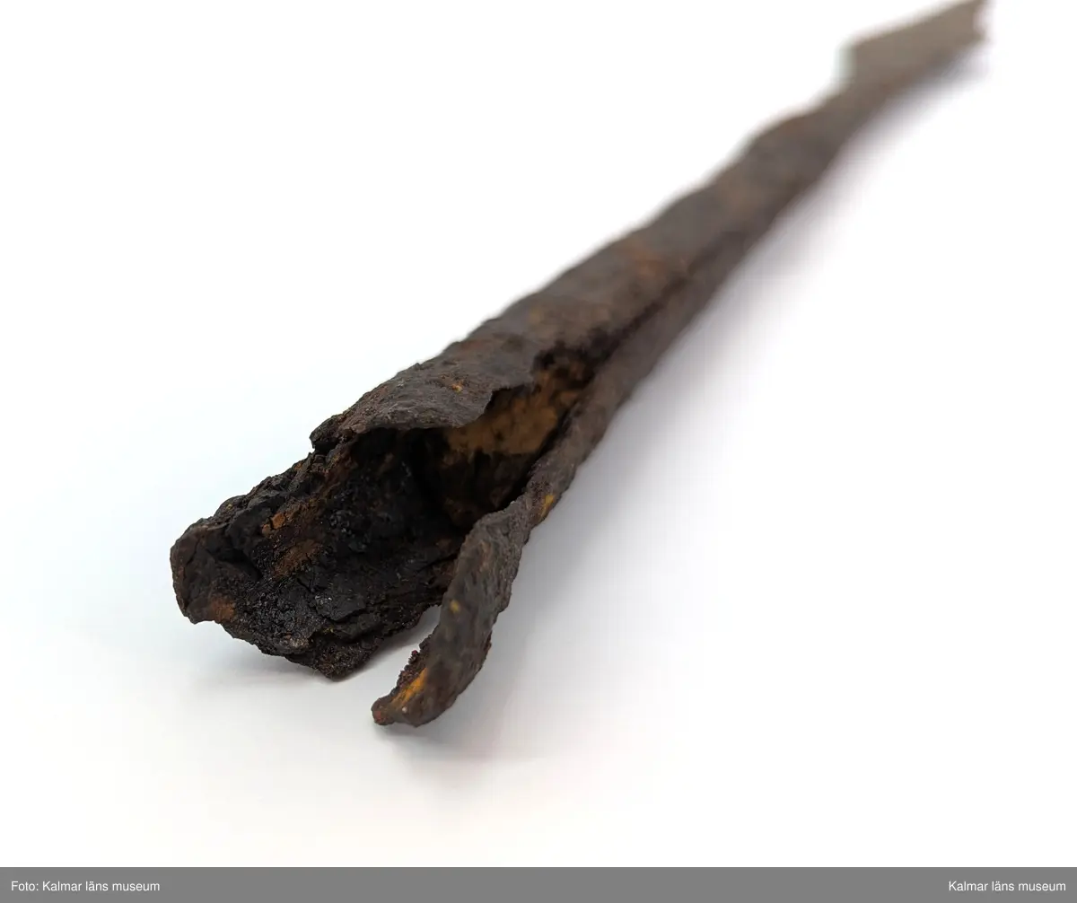 KLM 2498. Spjutspets. Lång med rombiskt blad. Holken är rund ner mot bladet men mer fyrkantig längre bak, där ett stycke trä sitter kvar.  Mått: längd 37 cm, därav holk 20 cm, bladets bredd 3,2 cm.