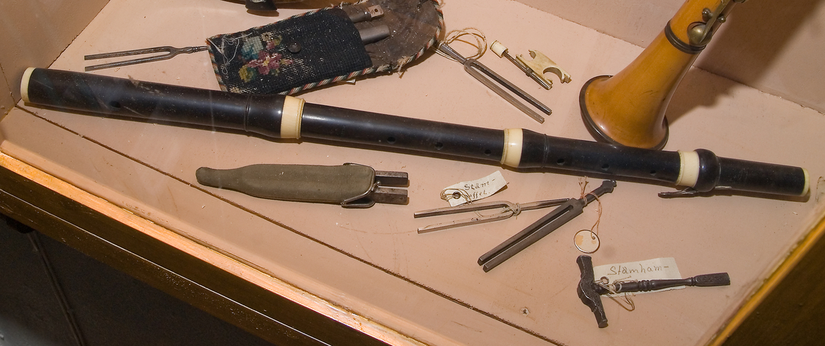 Tvärflöjt i mörkt trä (sannolikt grenadill) med klaffar av ben/horn. 4 delar. Något konisk. 1 klaff i silver med vulstlagring och kvadratisk platta.