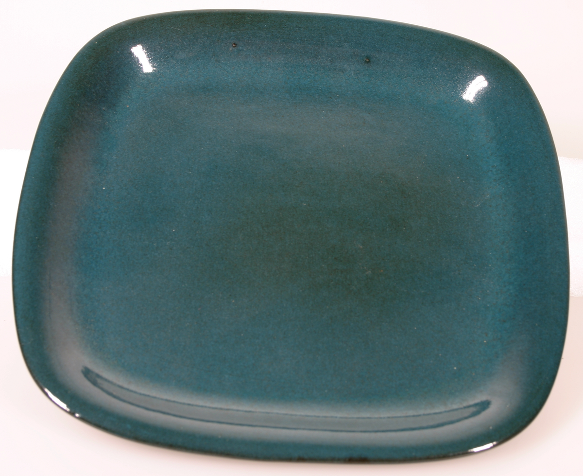 Fyrkantigt fat med rundade hörn och låga brätten. Blågrön på ovansidan, brun på undersidan. Stämplad: UE Sweden 2231 Abg