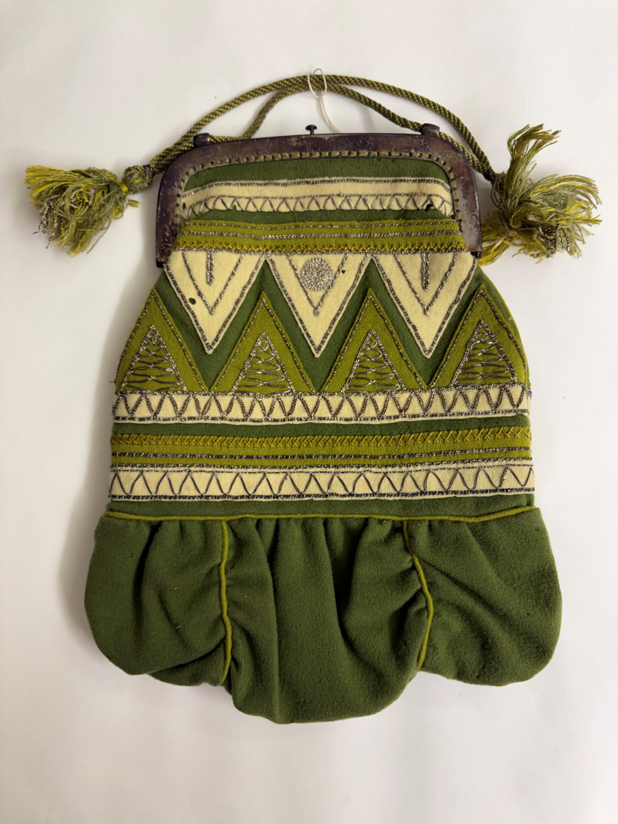 Av grönt tuskaftat ylle. Påsydda applikationer, broderi med silvertråd.