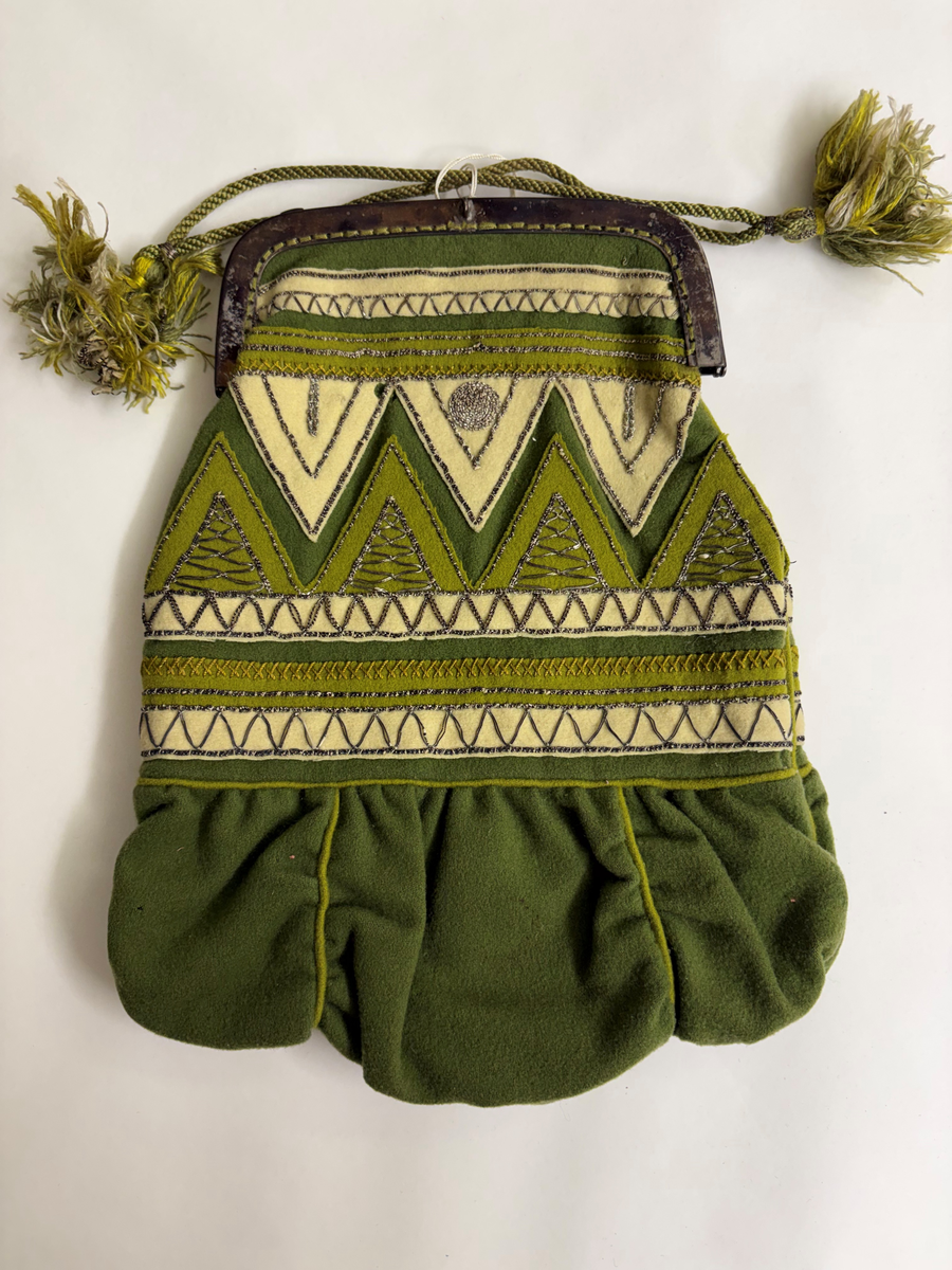 Av grönt tuskaftat ylle. Påsydda applikationer, broderi med silvertråd.