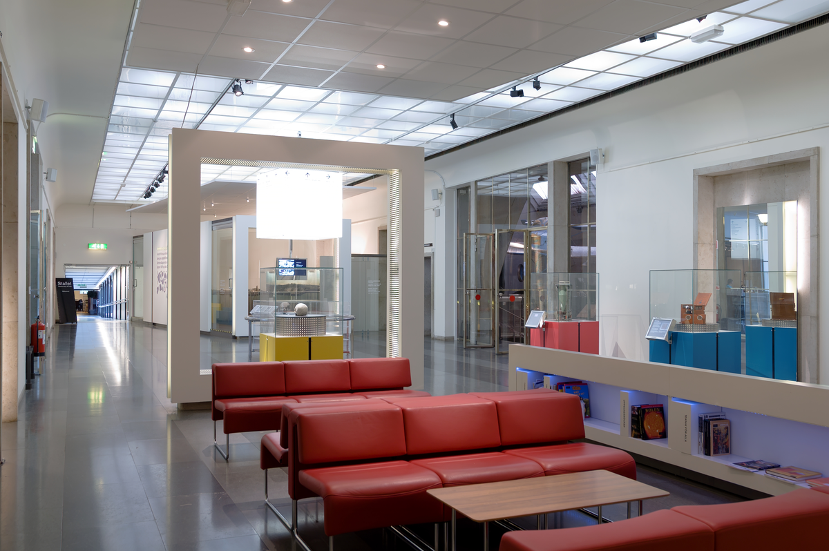 Sverigesalen i Tekniska museet. Halva Sverigesalen upptogs av utställningsmontrar för arkiv, bibliotek och föremålssamlingar "månadens". I den låga, långa montern visades kartor och bokuppslag. Längst bort syns glasgången till restaurang Stallet.