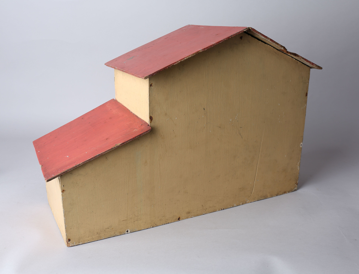 Rektangulært dukkehus i treverk med tre vegger, festet tak og dører i front. Huset er gult på utsiden og har tre etasjer, hvor loftet er lukket, men har et mindre hull i front. Taket er rødt. Dørene har vinduer med brunt listverk og hvite blondegardiner på innsiden. Tre gulvflater er belagt med grå linoleum, to gulvflater mangler belegg. Fire av rommene har tapet på veggene, alle i rikt detaljerte mønstre i flere farger. Taket i andre etasje har et hvitt intrikat mønster. Tomme rom uten særlige tegn til bruksområder.