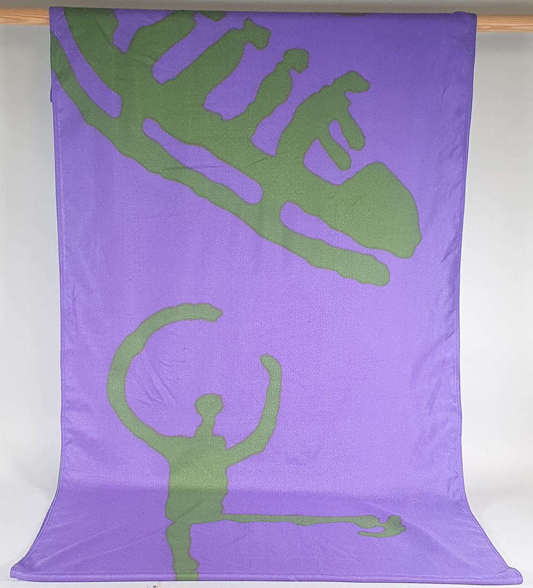 Grønt og lilla banner med deler av mønster fra piktogrammer - bob, kunstløp og fakkelmann. Krystallmønsteret inngikk i LOOCs designprogram.