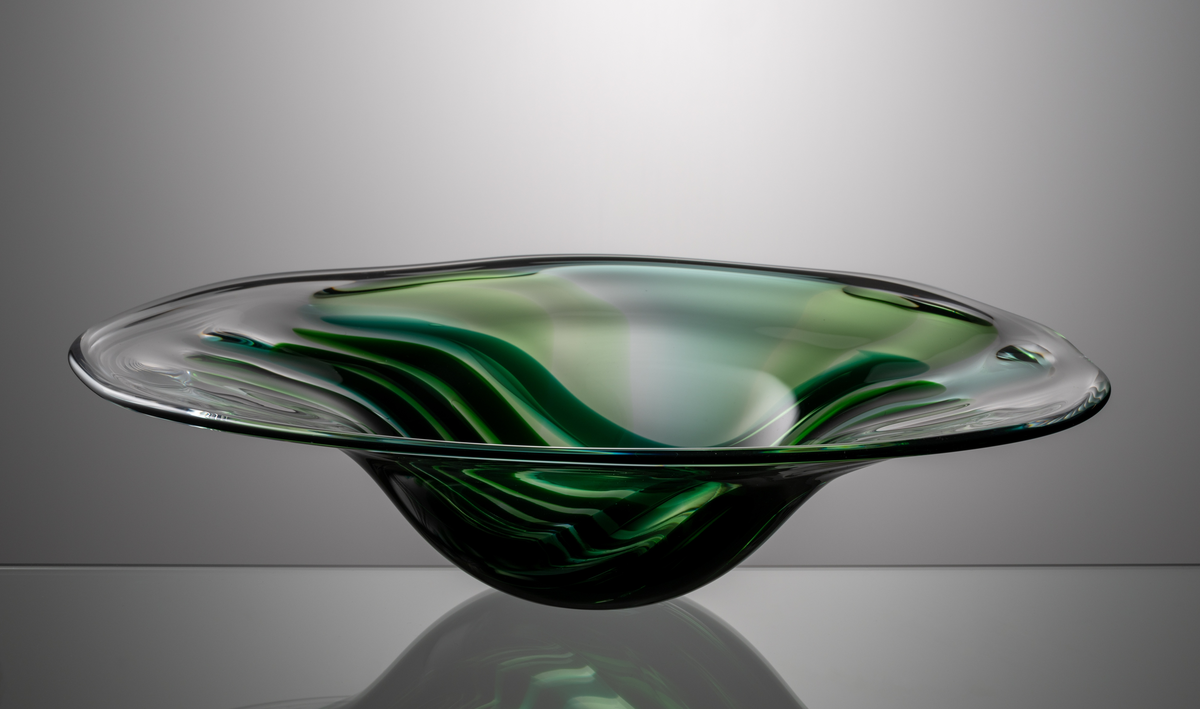 Formgivare: Lars Hellsten. Skål alt. fat. Oval form med generöst brätte. Dekor i form av avlånga fält i gröna nyanser. 
Troligen blåst av Ronny Fagerström 
(se M 20042)