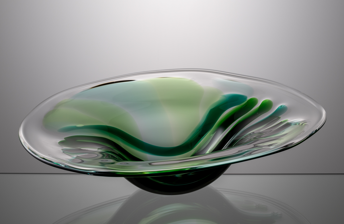 Formgivare: Lars Hellsten. Skål alt. fat. Oval form med generöst brätte. Dekor i form av avlånga fält i gröna nyanser. 
Troligen blåst av Ronny Fagerström 
(se M 20042)