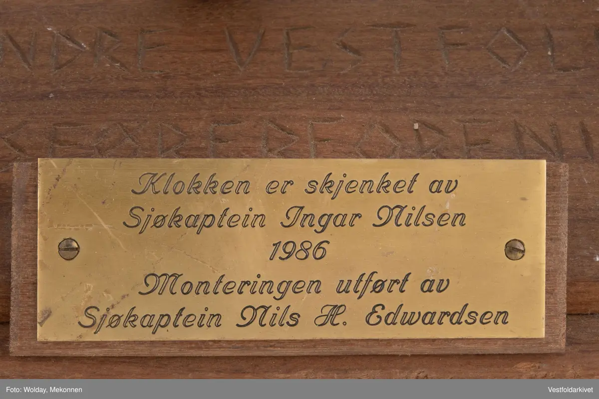 En klokke av metall, festet på et stativ dekorert med tauverk.