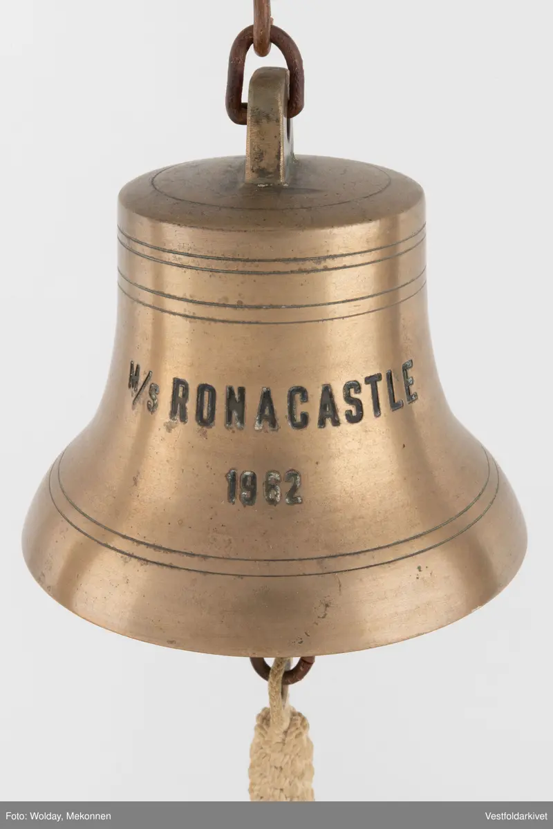 En klokke av metall, festet på et stativ dekorert med tauverk.