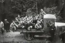 Lastebil med barn og ungdom på lasteplanet på 1920-talet.