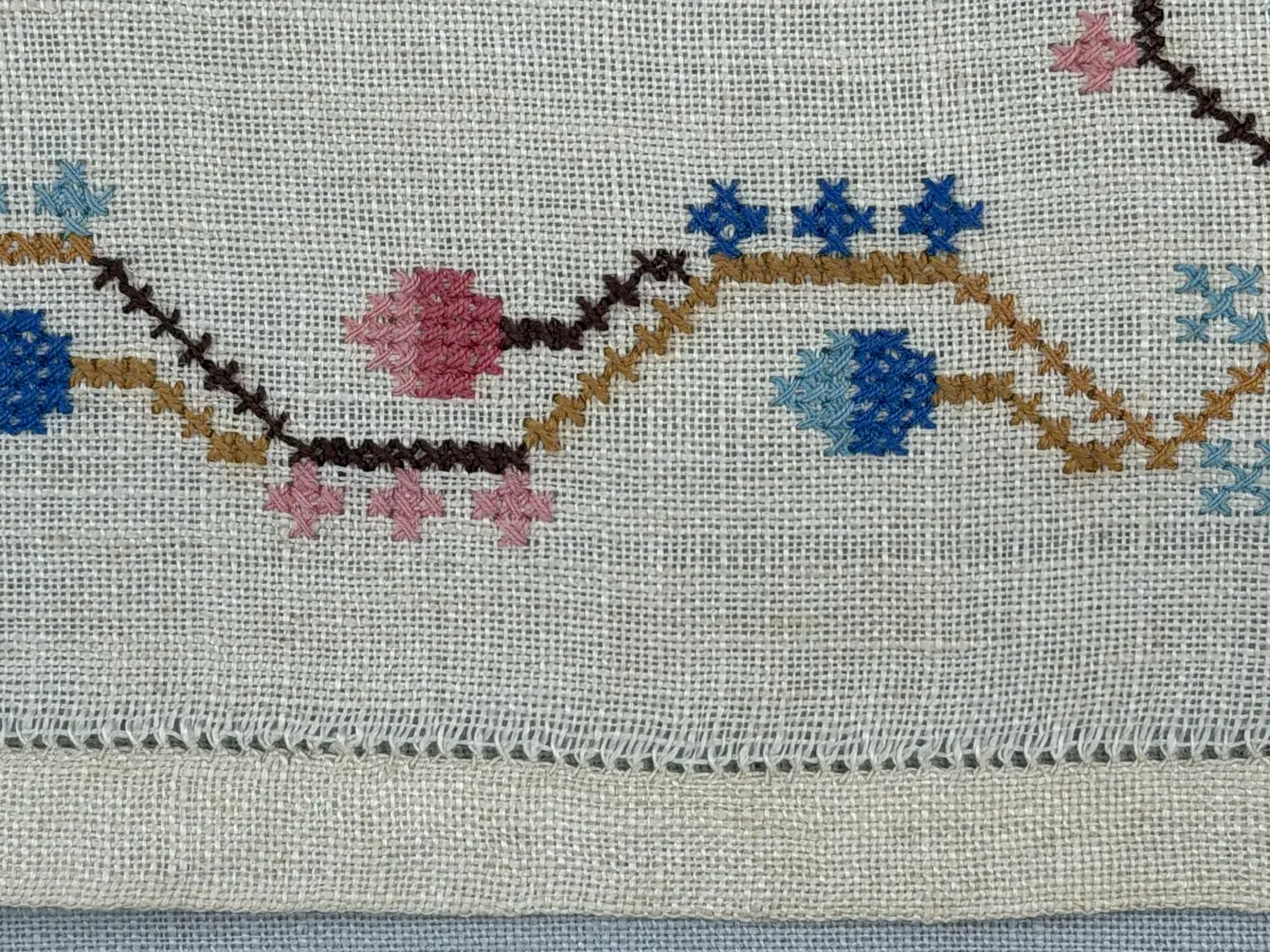 Duk gjord av linneväv med 15tr/cm i tuskaft och broderi utfört med dubbelt bomullsgarn i korsstygn sydda över tre trådar. Duken har 11mm bred dubbelvikt fåll runt om fastsydd med en enkel hålsöm samt sneda hörn, vilka är sömmade med kaststygn.
