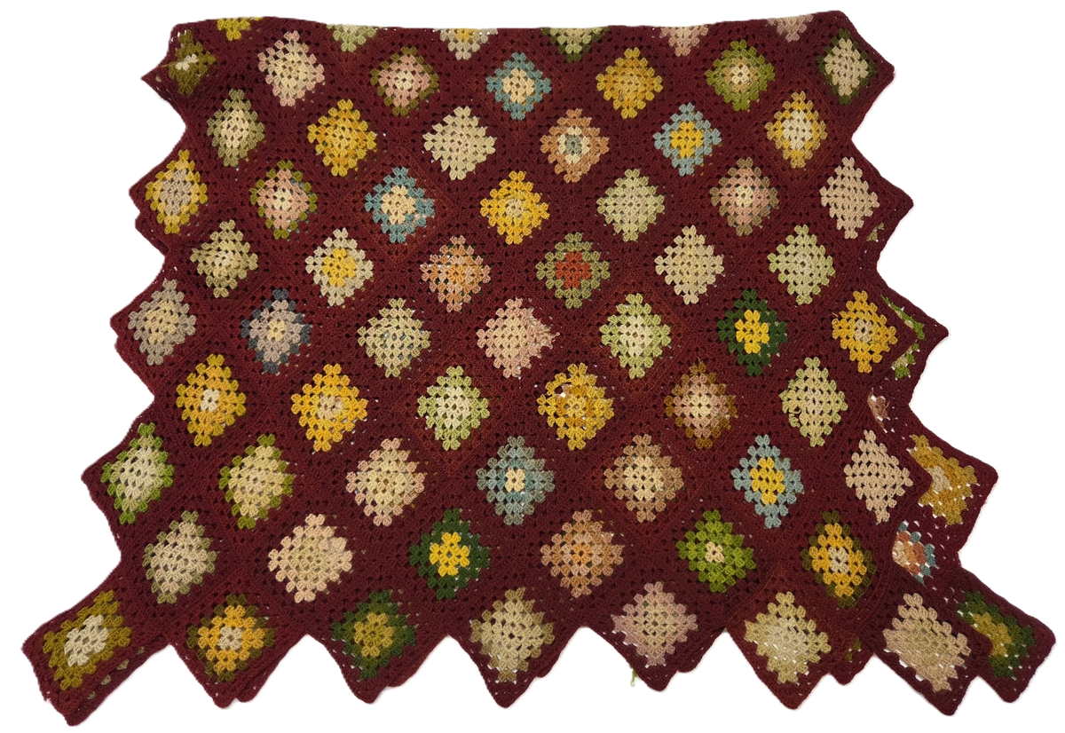 Filt. Virkad uddkantig filt. Vinröd bottenfärg med rutor i gult, grönt, rosa och ljusblått.