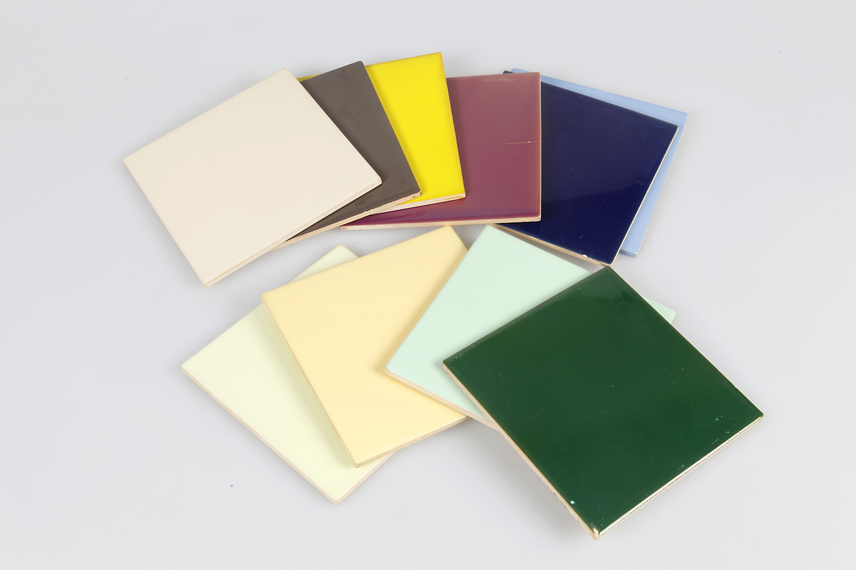 60 st kvadratiska, enfärgade glaserade kakelplattor av gulaktig lera. Merparten stämplade med UE-stämpel och SWEDEN. Varierande färger (se information).