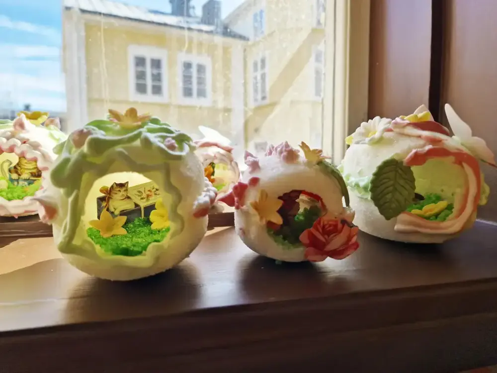 Tre tittägg står på ett fönsterbräde med ett hus utanför fönstret.