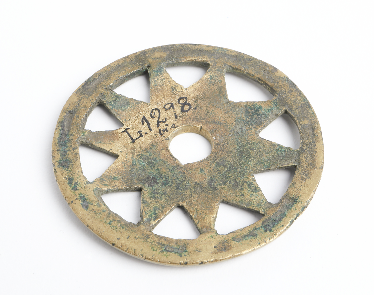 Hjulformat ornament av mässing.Förmodligen till ett betsel eller knivatyg. 

Inskrivet i huvudbok år 1873.
