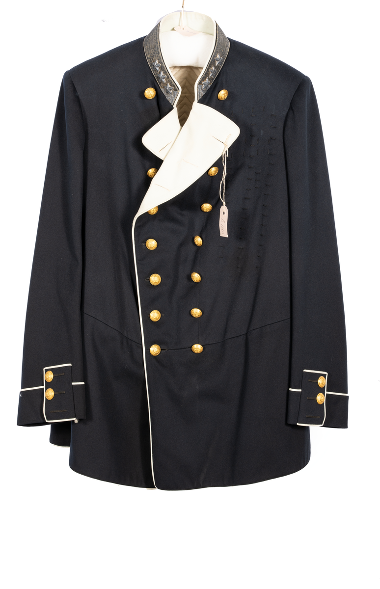 Amiralsvapenrock, vitfodrad med vita slag av kläde, vita passpoaler. Galonerad krage med tre broderade silverstjärnor. Åtta knappar på varje sida, tre på ärmen samt sex i ryggen. En inner- och två bakfickor.
Har tillhört Kung Oscar II.