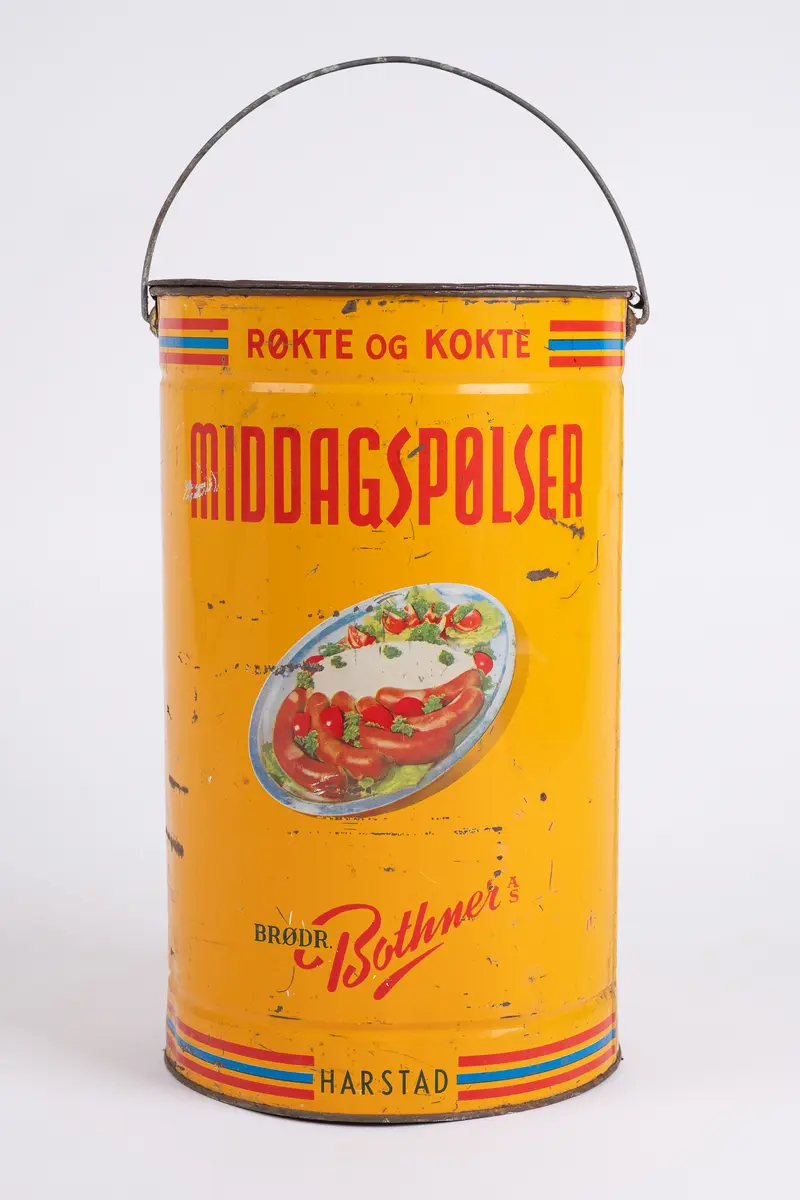 Spann. Sylinderformet. Emaljert blikkmetall. Lokk med riller. Fleksibel bøylehank i metall. Illustrasjon på 2 sider av serveringsfat med pølser. Skrift.