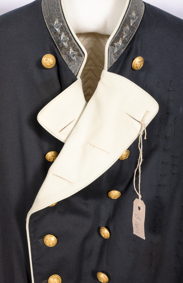 Amiralsvapenrock, vitfodrad med vita slag av kläde, vita passpoaler. Galonerad krage med tre broderade silverstjärnor. Åtta knappar på varje sida, tre på ärmen samt sex i ryggen. En inner- och två bakfickor.
Har tillhört Kung Oscar II.