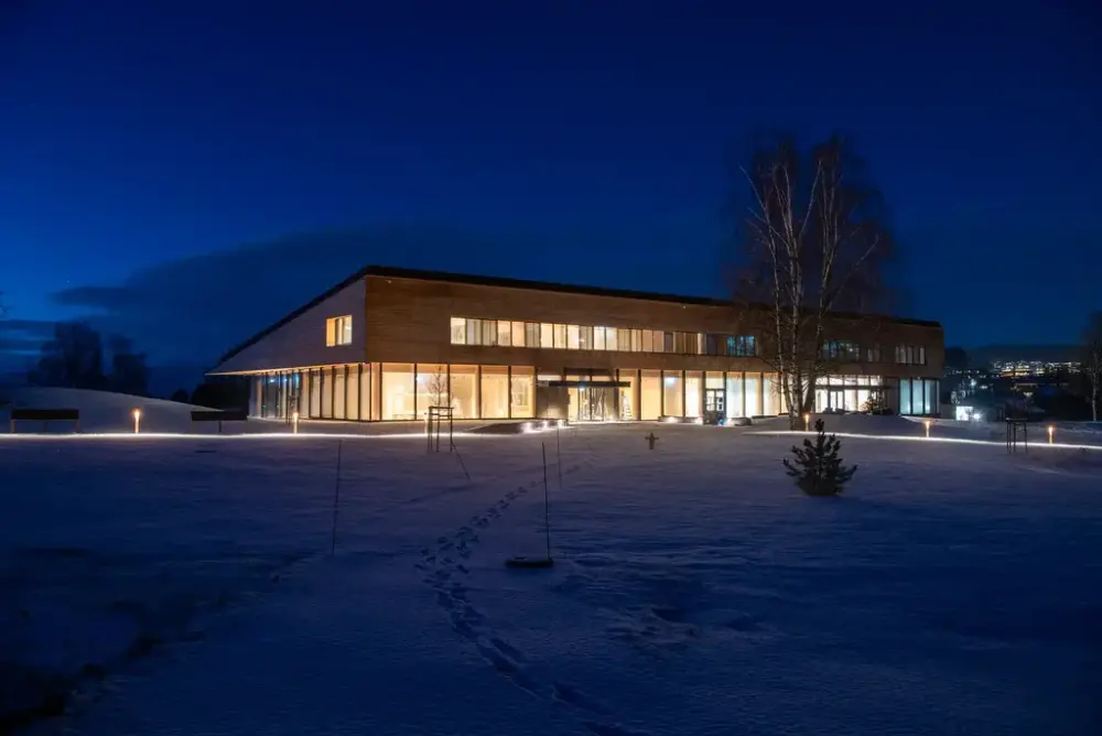 Kveldsbilde av Anno Regionalt Historiesenter i Hamar med opplyst museumsbygning og snødekt vinterlandskap.