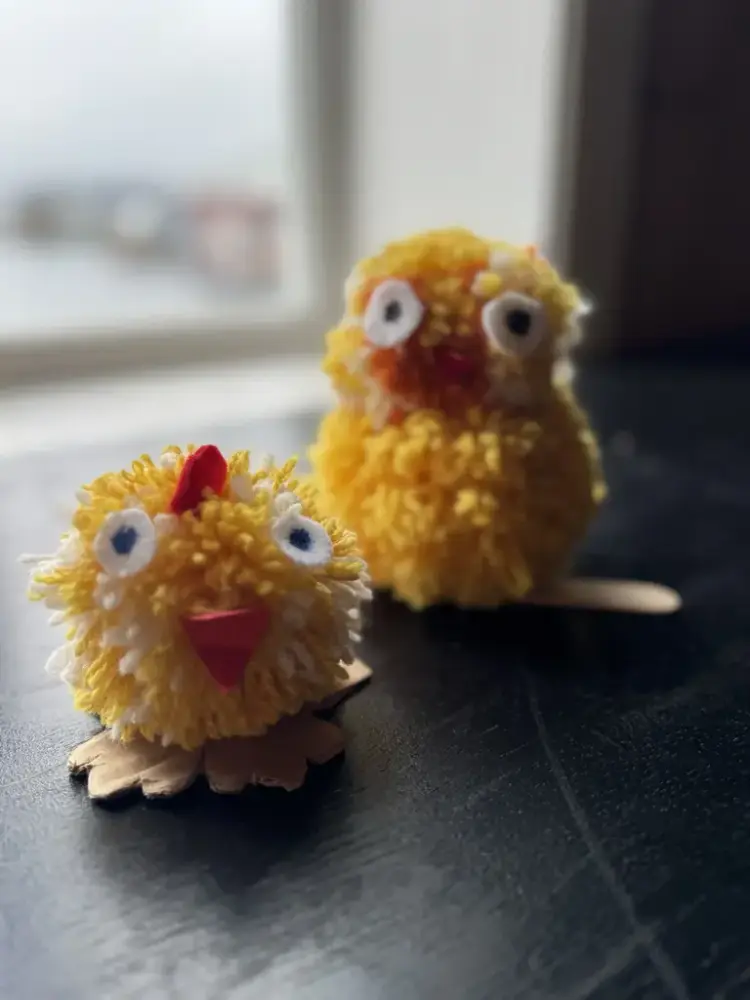 to gule påskekyllinger, laget av garnrester, to dusker satt oppå hverandre