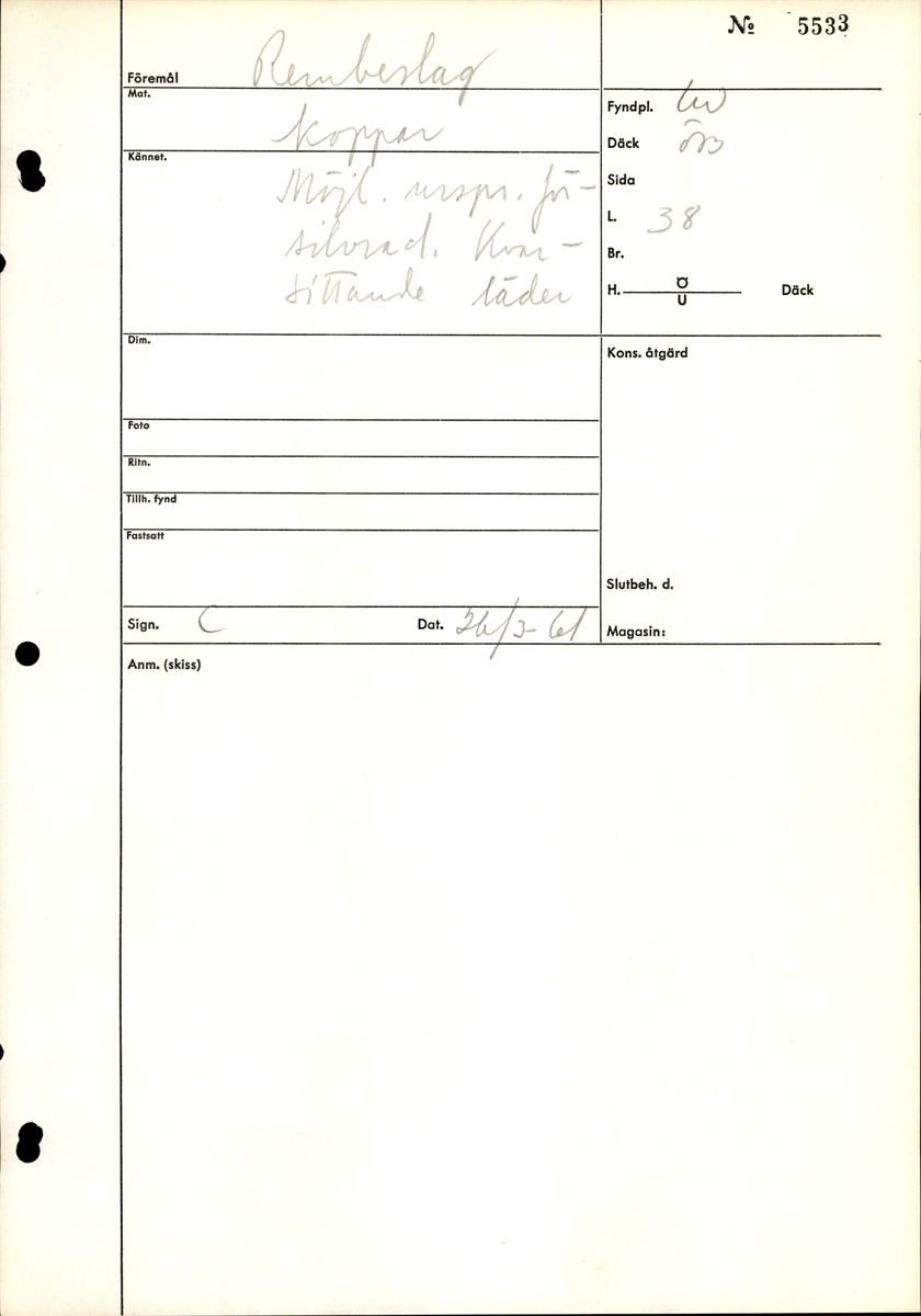 Remändebeslag av koppar med kvarsittande fragmentariska rester av läder. Lädret har fästs med stift genom beslaget. Beslaget är ärgat men relativt välbevarat.