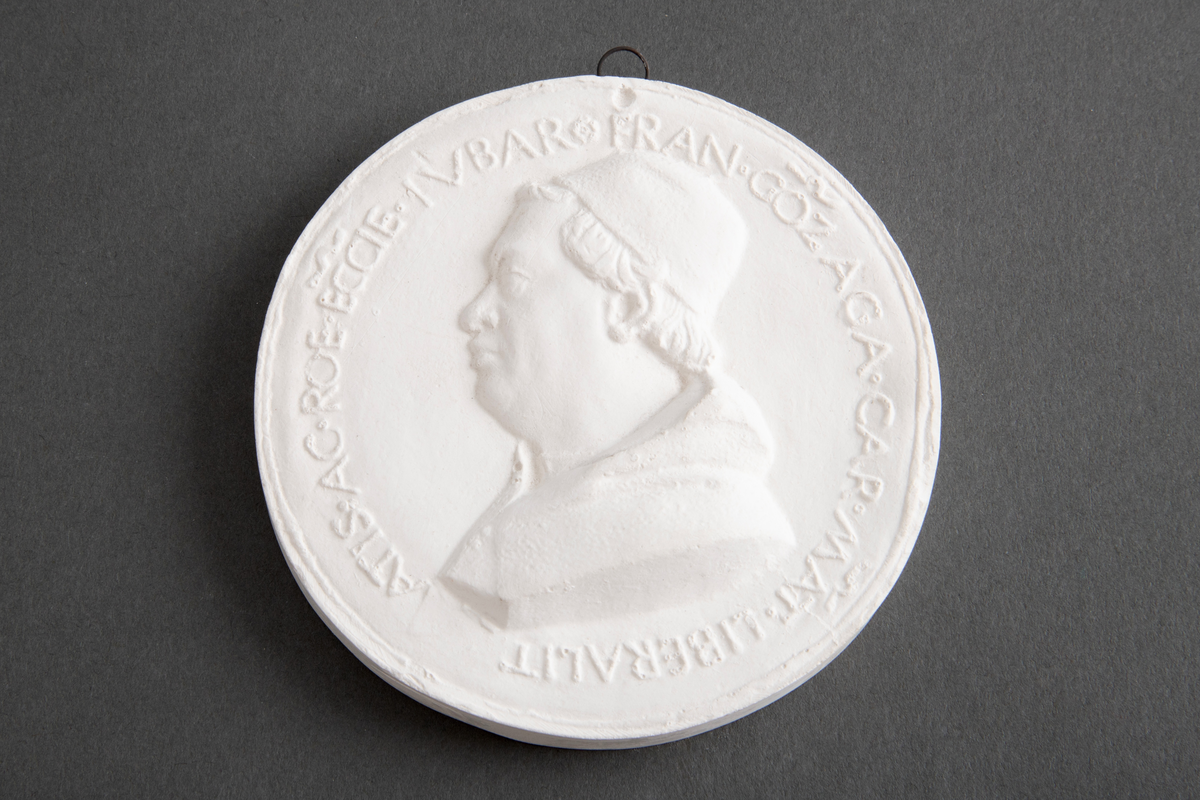 Avstøpning av bronseplakett. Hempe i metall for opphenging.