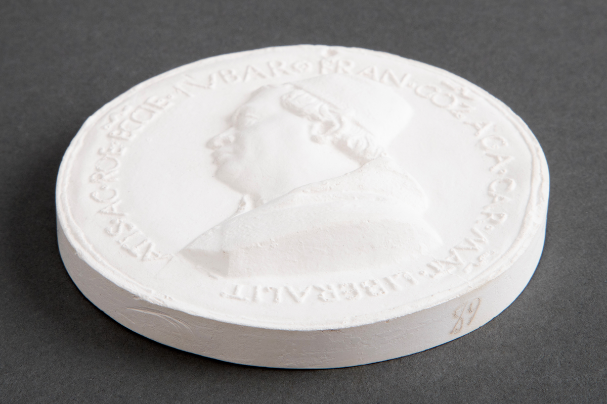 Avstøpning av bronseplakett. Hempe i metall for opphenging.