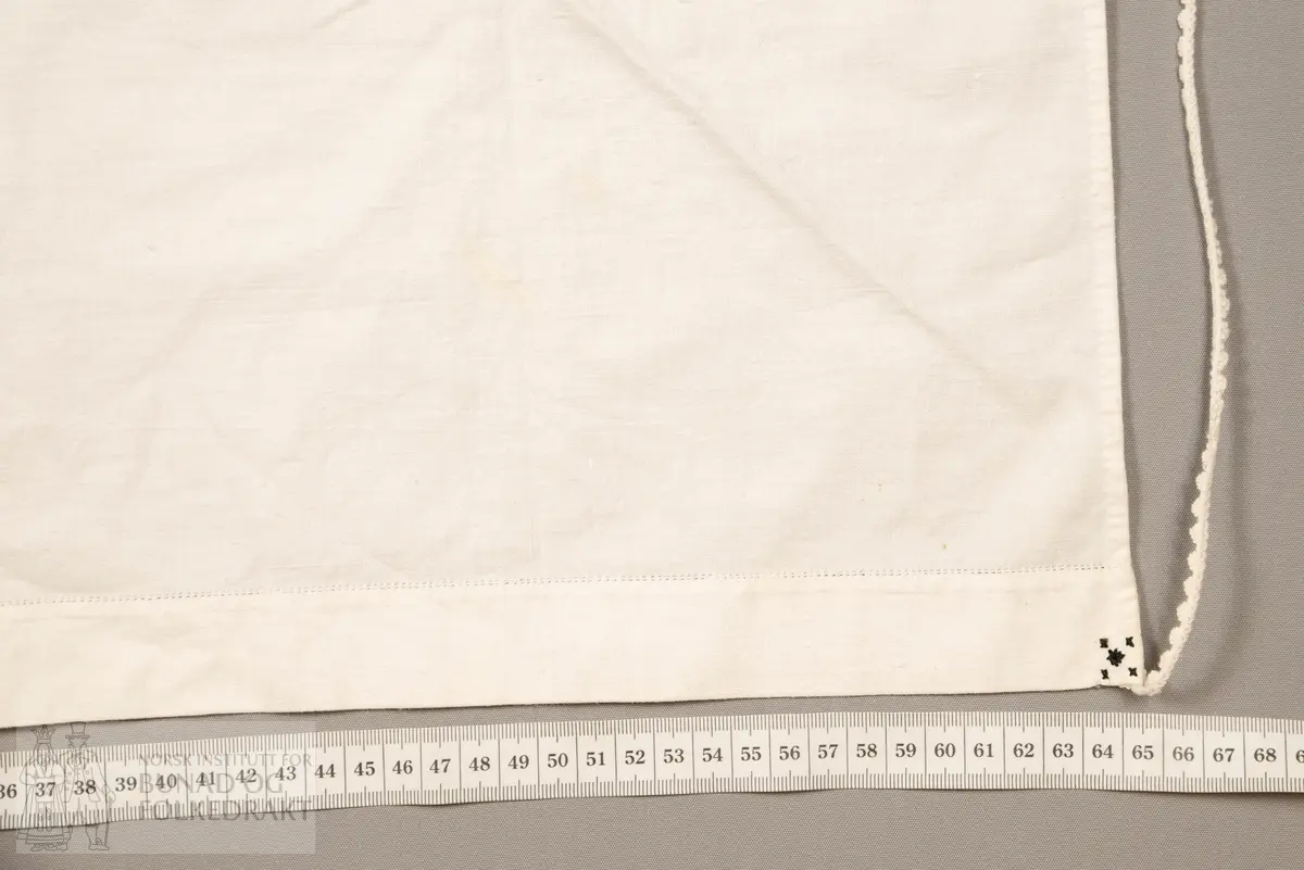 Skaut sydd av stødig, fast bomullslerret (24 tråder x 24 tråder per cm.). Bretta diagonalt. Broderi i eine snippen, av svart, tjukk silketråd og glasperler i mellomblå, mørk transparant blå, transparant grøn, transparant gul, og ei perle transparant raud.
Innbrodert med korssting initialane: "M.L.D.H."
Kjedesting, stilkesting og korssting.
Langs båe sider av den broderte snippen er bretta ein brei fald sydd ned med enkel holfald.
Også jare langs ei side og ein smalbretta fald sydd ned med små faldesting i den fjerde sida.
Knyteband av smalt, kvitt blondeband i bomull.

Om skautet i "Hovdatyet" av Eli Drønen: "Skautet var av lerret og sydd med svart tråd i korssting i nakken, ca. 67 x 67 cm. Skautebanda vart festa i to endar av skauten, dei er i ripsvevnad 58 cm x 1,3. Skautet vart lagt i trekant og sett på hua. Det vart kryssa bak, og skautspissane rakk til øyrene, og vidare vart skautebanda kryssa framme ca. 3 cm innpå skautet og ført vidare og knytt bak under skautet. Endene av banda vart putta innunder skautet. (...) Skautet var brukt utanpå rundhua, når dei gjekk til kyrkje, i gjestebod og i bryllaup."