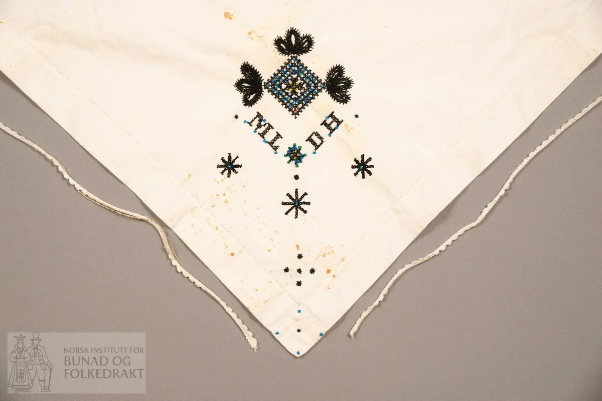 Skaut sydd av stødig, fast bomullslerret (24 tråder x 24 tråder per cm.). Bretta diagonalt. Broderi i eine snippen, av svart, tjukk silketråd og glasperler i mellomblå, mørk transparant blå, transparant grøn, transparant gul, og ei perle transparant raud.
Innbrodert med korssting initialane: "M.L.D.H."
Kjedesting, stilkesting og korssting.
Langs båe sider av den broderte snippen er bretta ein brei fald sydd ned med enkel holfald.
Også jare langs ei side og ein smalbretta fald sydd ned med små faldesting i den fjerde sida.
Knyteband av smalt, kvitt blondeband i bomull.

Om skautet i "Hovdatyet" av Eli Drønen: "Skautet var av lerret og sydd med svart tråd i korssting i nakken, ca. 67 x 67 cm. Skautebanda vart festa i to endar av skauten, dei er i ripsvevnad 58 cm x 1,3. Skautet vart lagt i trekant og sett på hua. Det vart kryssa bak, og skautspissane rakk til øyrene, og vidare vart skautebanda kryssa framme ca. 3 cm innpå skautet og ført vidare og knytt bak under skautet. Endene av banda vart putta innunder skautet. (...) Skautet var brukt utanpå rundhua, når dei gjekk til kyrkje, i gjestebod og i bryllaup."