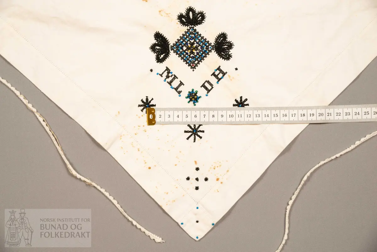 Skaut sydd av stødig, fast bomullslerret (24 tråder x 24 tråder per cm.). Bretta diagonalt. Broderi i eine snippen, av svart, tjukk silketråd og glasperler i mellomblå, mørk transparant blå, transparant grøn, transparant gul, og ei perle transparant raud.
Innbrodert med korssting initialane: "M.L.D.H."
Kjedesting, stilkesting og korssting.
Langs båe sider av den broderte snippen er bretta ein brei fald sydd ned med enkel holfald.
Også jare langs ei side og ein smalbretta fald sydd ned med små faldesting i den fjerde sida.
Knyteband av smalt, kvitt blondeband i bomull.

Om skautet i "Hovdatyet" av Eli Drønen: "Skautet var av lerret og sydd med svart tråd i korssting i nakken, ca. 67 x 67 cm. Skautebanda vart festa i to endar av skauten, dei er i ripsvevnad 58 cm x 1,3. Skautet vart lagt i trekant og sett på hua. Det vart kryssa bak, og skautspissane rakk til øyrene, og vidare vart skautebanda kryssa framme ca. 3 cm innpå skautet og ført vidare og knytt bak under skautet. Endene av banda vart putta innunder skautet. (...) Skautet var brukt utanpå rundhua, når dei gjekk til kyrkje, i gjestebod og i bryllaup."