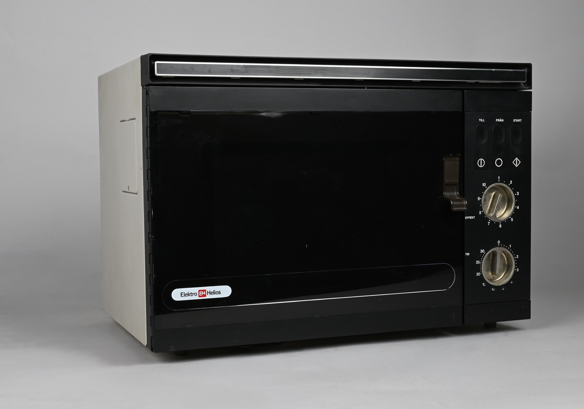 Mikrovågsugn med brun front av märket Elektro Helios. Infällda vred i blank metall för tid och effekt. Infällda tryckknappar för start, samt on & off.