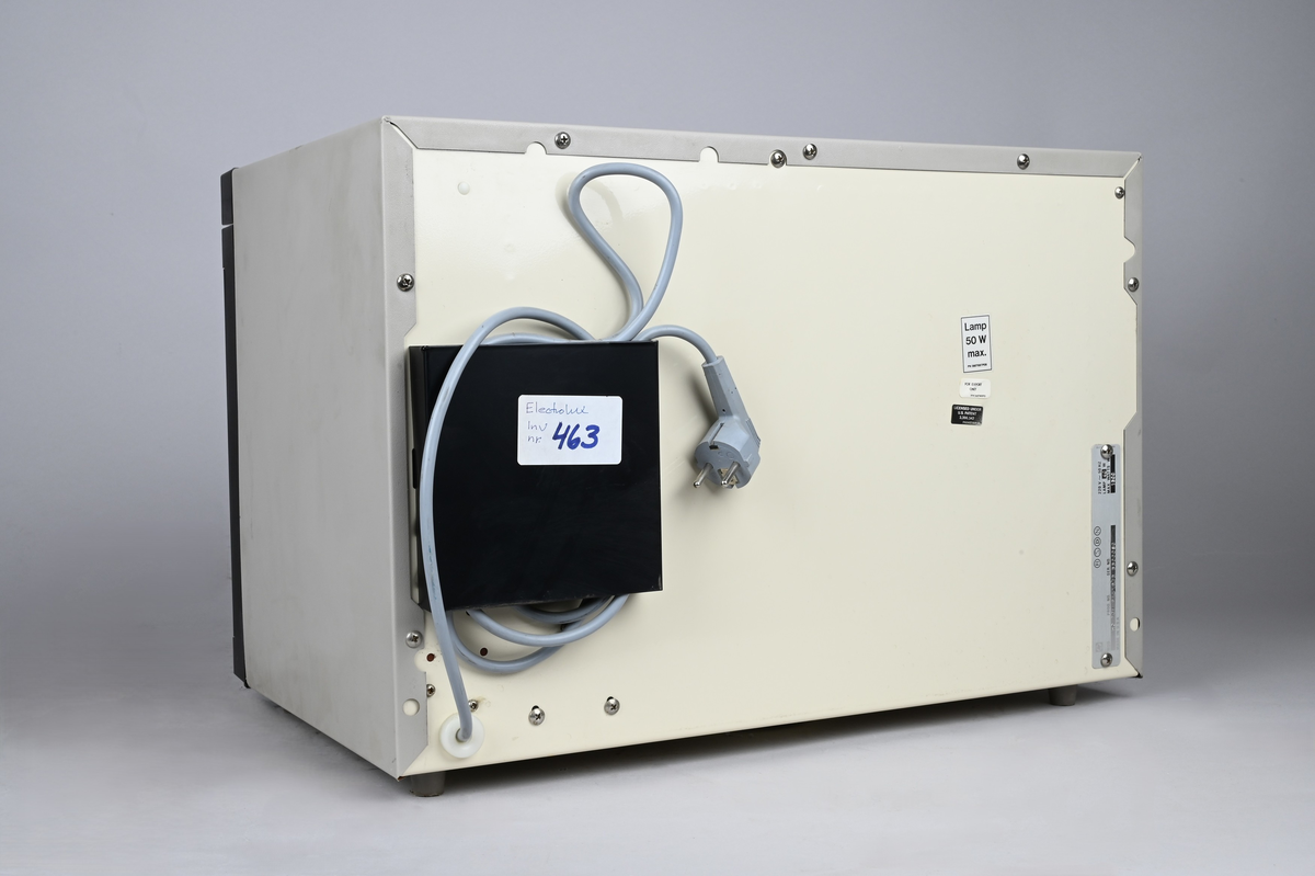 Mikrovågsugn med brun front av märket Elektro Helios. Infällda vred i blank metall för tid och effekt. Infällda tryckknappar för start, samt on & off.