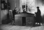Två män i arbete vid skrivbord på Brattfors herrgårds skogskontor. Enligt reklamfilmen UHB-bruket 1945.