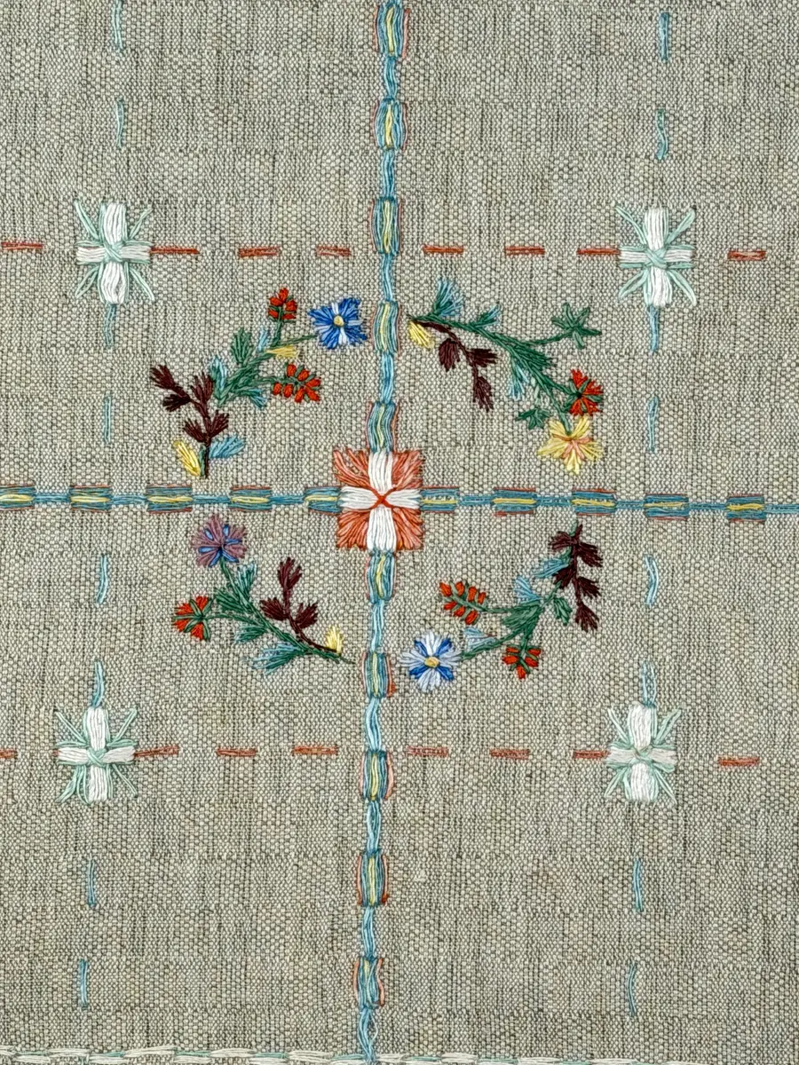 Duk gjord av halvlinne i sålldräll och broderi utfört med lingarn i förstygn, plattsöm och stjälksöm. Duken har 1cm bred dubbelvikt fåll runt om samt sneda hörn, vilka är sydda med kaststygn.