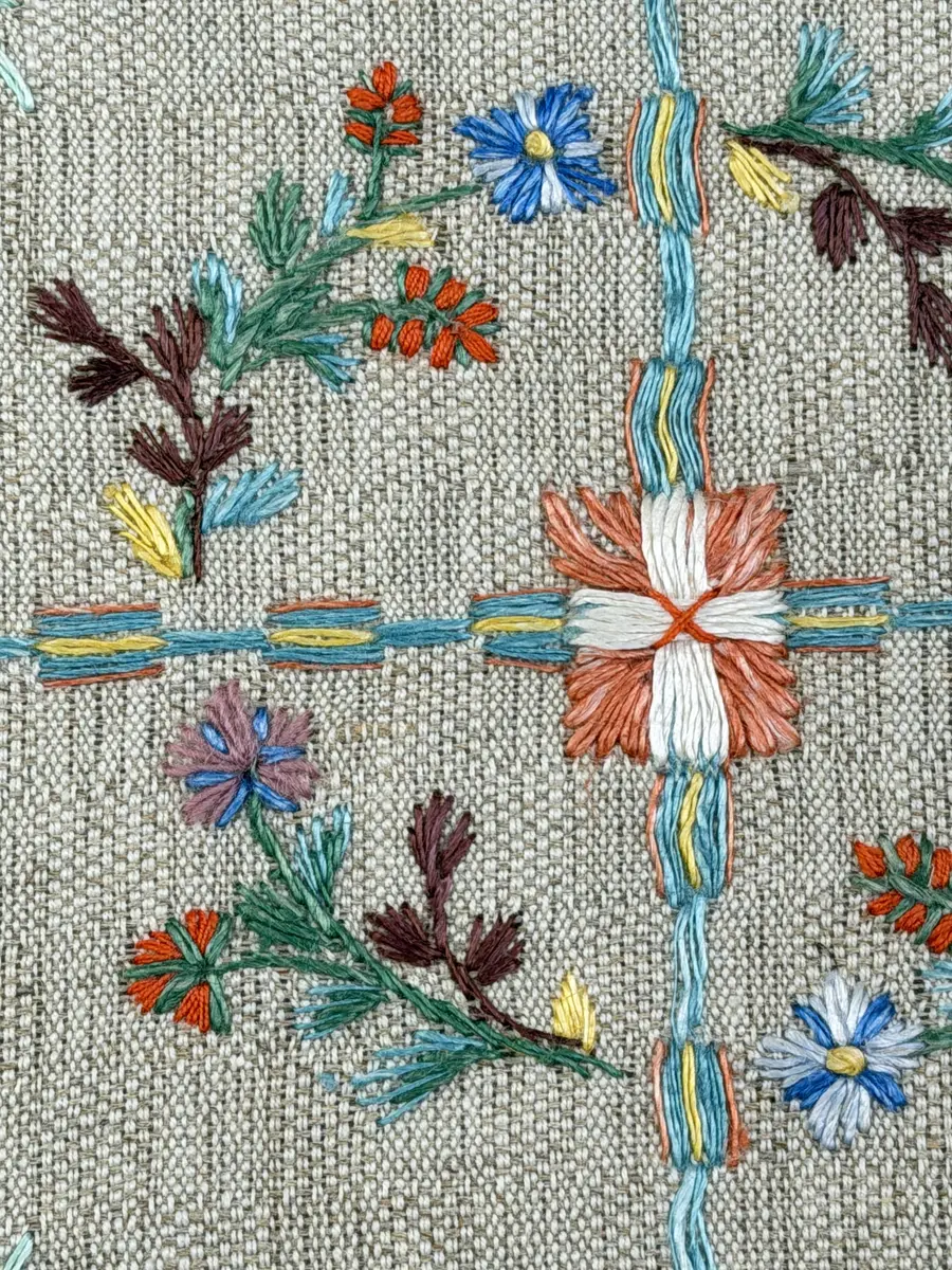 Duk gjord av halvlinne i sålldräll och broderi utfört med lingarn i förstygn, plattsöm och stjälksöm. Duken har 1cm bred dubbelvikt fåll runt om samt sneda hörn, vilka är sydda med kaststygn.