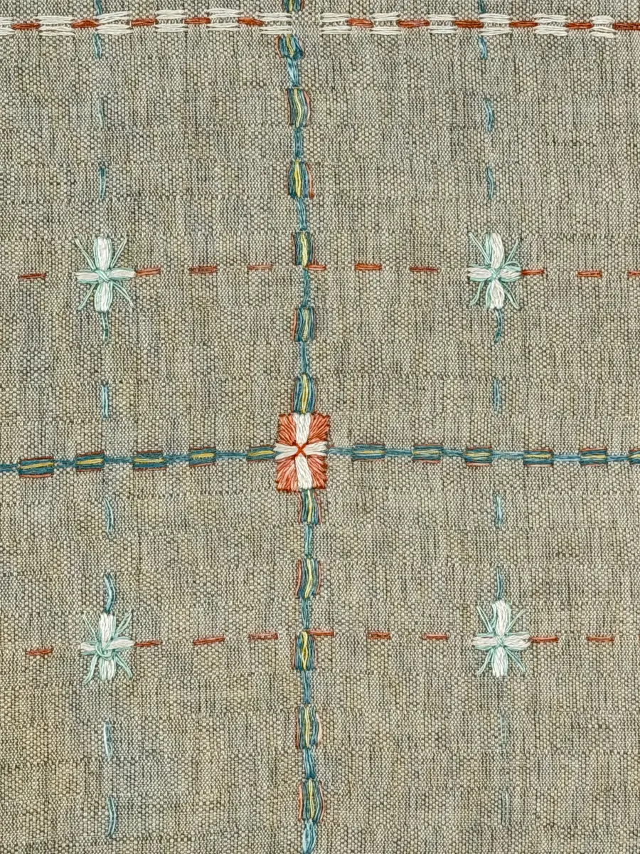 Duk gjord av halvlinne i sålldräll och broderi utfört med lingarn i förstygn, plattsöm och stjälksöm. Duken har 1cm bred dubbelvikt fåll runt om samt sneda hörn, vilka är sydda med kaststygn.