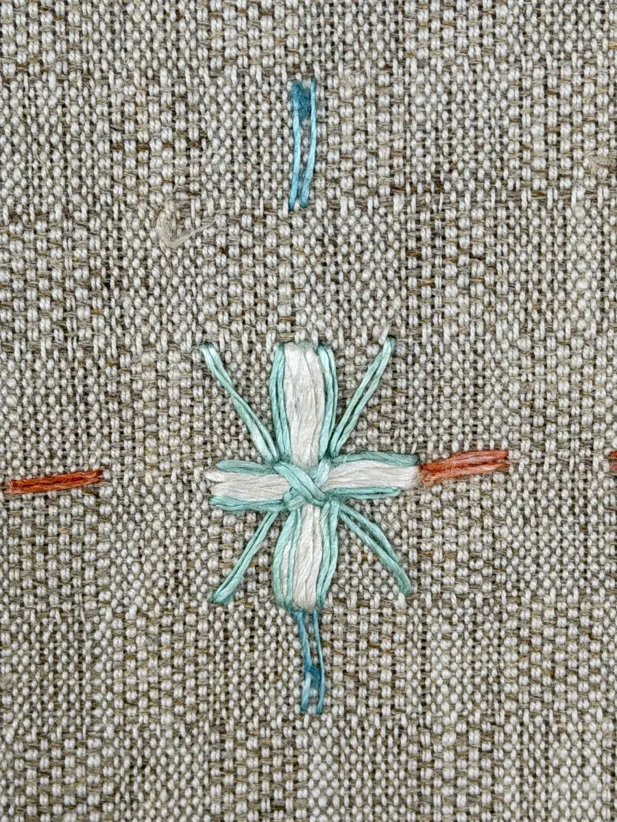 Duk gjord av halvlinne i sålldräll och broderi utfört med lingarn i förstygn, plattsöm och stjälksöm. Duken har 1cm bred dubbelvikt fåll runt om samt sneda hörn, vilka är sydda med kaststygn.