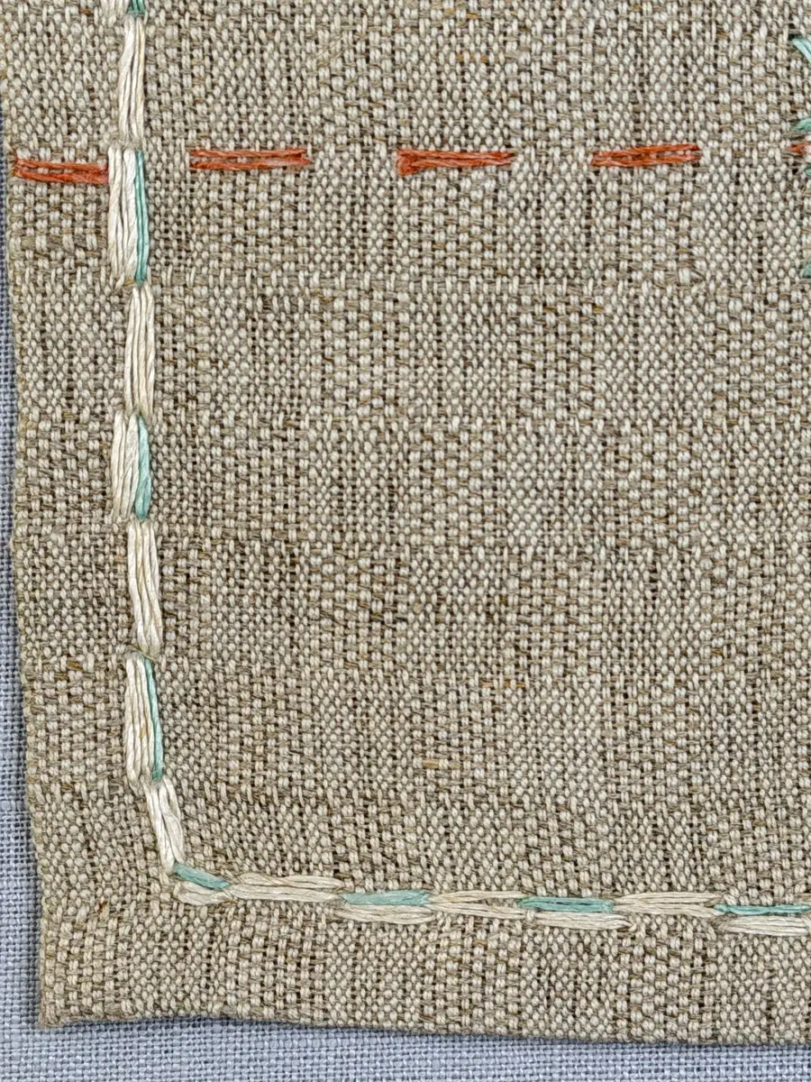 Duk gjord av halvlinne i sålldräll och broderi utfört med lingarn i förstygn, plattsöm och stjälksöm. Duken har 1cm bred dubbelvikt fåll runt om samt sneda hörn, vilka är sydda med kaststygn.