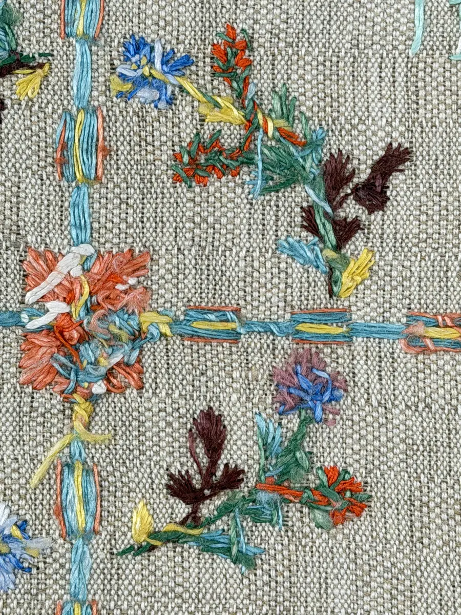 Duk gjord av halvlinne i sålldräll och broderi utfört med lingarn i förstygn, plattsöm och stjälksöm. Duken har 1cm bred dubbelvikt fåll runt om samt sneda hörn, vilka är sydda med kaststygn.