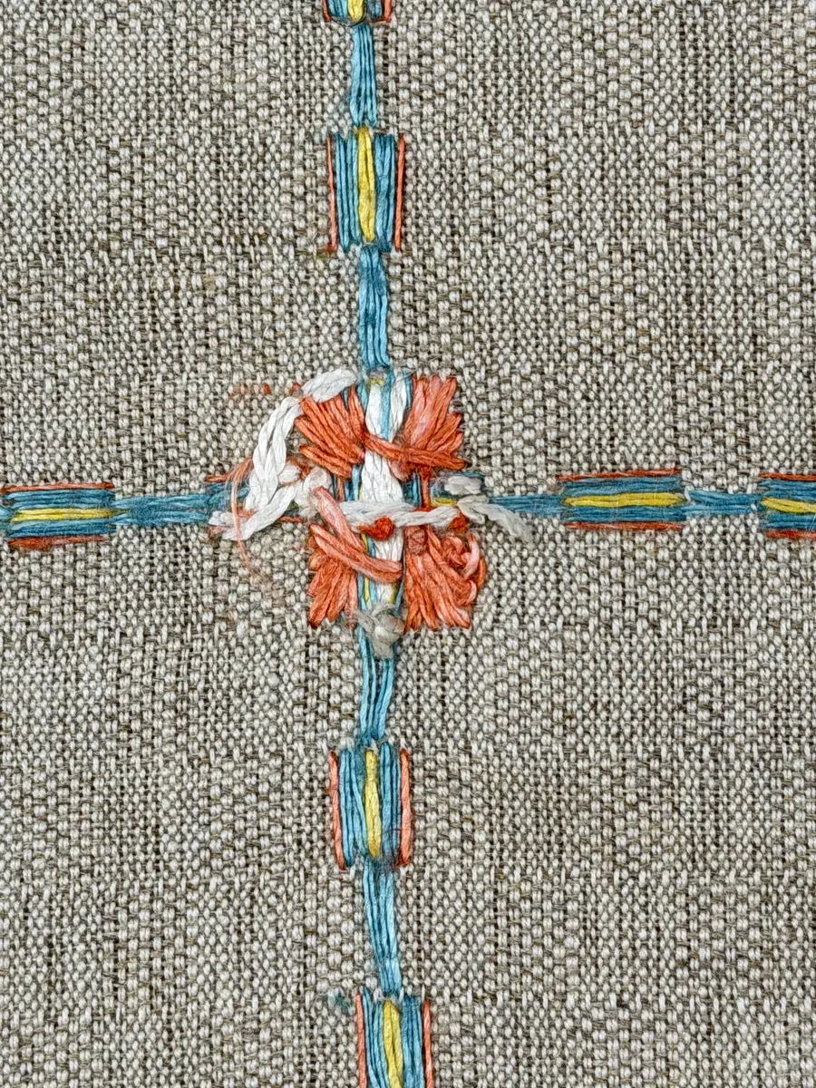 Duk gjord av halvlinne i sålldräll och broderi utfört med lingarn i förstygn, plattsöm och stjälksöm. Duken har 1cm bred dubbelvikt fåll runt om samt sneda hörn, vilka är sydda med kaststygn.