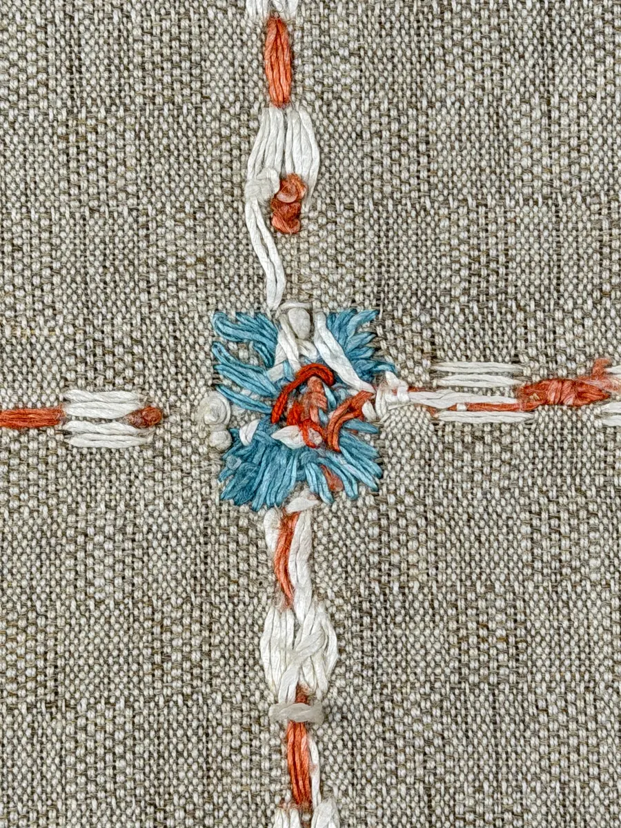 Duk gjord av halvlinne i sålldräll och broderi utfört med lingarn i förstygn, plattsöm och stjälksöm. Duken har 1cm bred dubbelvikt fåll runt om samt sneda hörn, vilka är sydda med kaststygn.