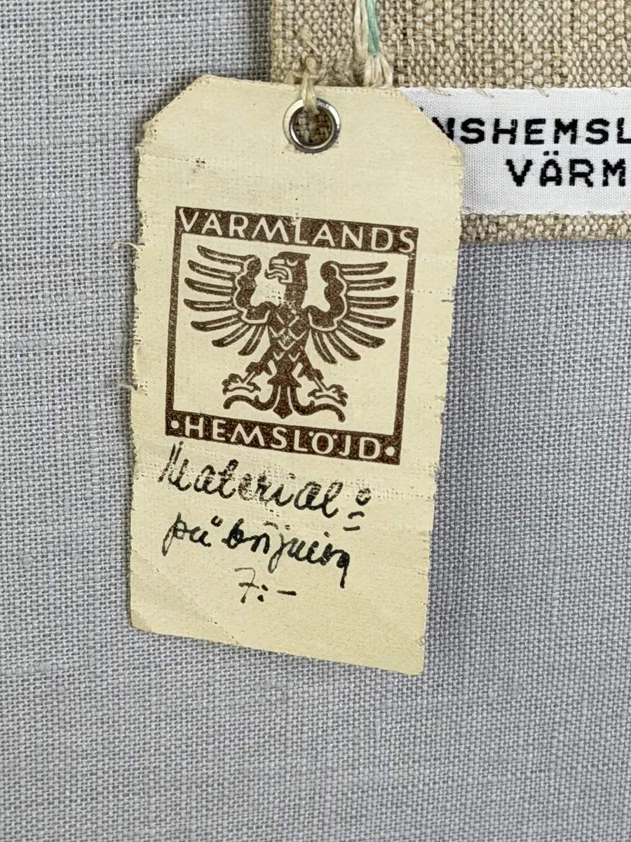 Duk gjord av halvlinne i sålldräll och broderi utfört med lingarn i förstygn, plattsöm och stjälksöm. Duken har 1cm bred dubbelvikt fåll runt om samt sneda hörn, vilka är sydda med kaststygn.